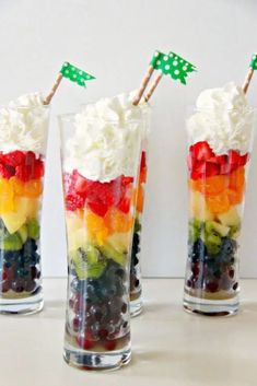 three glasses filled with fruit and whipped cream on top of a table next to each other