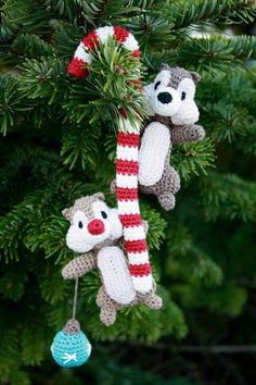 two stuffed animals are hanging from a christmas tree ornament on a pine branch