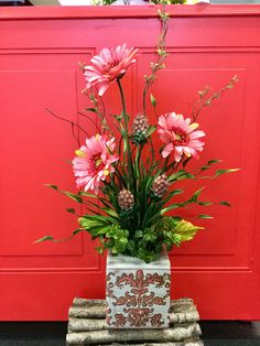 a vase filled with pink flowers sitting on top of a wooden table next to a red door