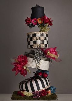 a multi - tiered cake with flowers and ribbons on top is displayed in front of a gray background