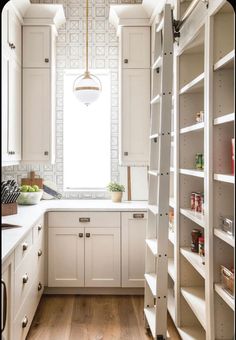 a kitchen filled with lots of white cupboards and counter top next to a window