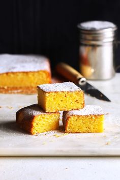 three pieces of yellow cake sitting on top of a cutting board next to a knife