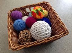 a basket filled with lots of different colored crocheted balls and yarn on top of a table