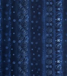 a blue curtain with white dots and circles on it's side, in front of a window