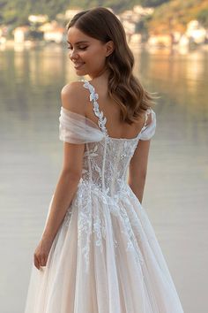 a woman in a wedding dress standing by the water