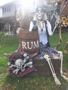 two skeleton statues sitting in front of a barrel with rum on it's side