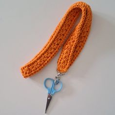 an orange crocheted lanyard with a blue pair of scissors attached to it