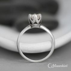 This beautiful Sterling Silver Crown Solitaire features a 6 mm faceted stone, set securely in a six-prong mounting. The solitaire has been the archetypical engagement ring style since its introduction in 1886. This version features delicate crown detailing on the stone mounting, and tapers gracefully to a 1.8 mm wide band. Although this ring isn't wide enough for our inside ring engraving, it pairs well with many of the other bands we offer! The ring shown above features a 6 mm faceted Lab White White Sapphire Solitaire Ring, Nature Inspired Wedding Bands, Crown Wedding Ring, Crown Engagement Ring, Diamond Alternative Engagement Ring, Silver Crown Ring, Most Popular Engagement Rings, Sapphire Solitaire Ring, White Sapphire Engagement Ring