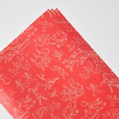 red wrapping paper with drawings on it sitting on top of a white table next to a wall