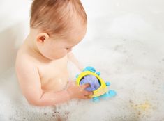 a baby playing with a toy in the bathtub filled with water and foams