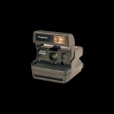 an old polaroid camera on a black background