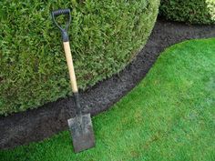 a shovel is stuck in the ground next to a hedge