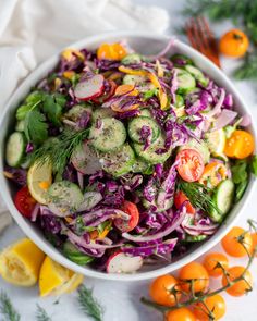 a salad with cucumbers, red cabbage and tomatoes in a white bowl on a table