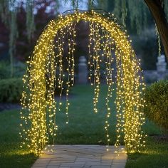 a lighted archway in the middle of a garden