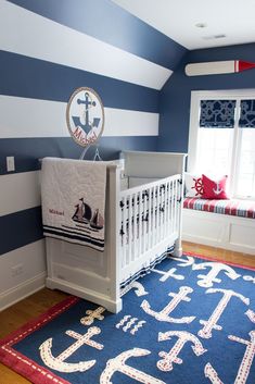 a baby's room with blue and white stripes on the walls, crib bedding, and rug