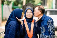 two people standing next to each other with a graduation cap on their head and an orange scarf around their neck