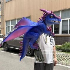 a man is holding a blue and purple dragon statue in front of a large building