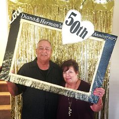 a man and woman pose for a photo in front of a 50th anniversary sign with gold streamers