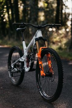 a white and orange bike parked on the side of a road in front of trees