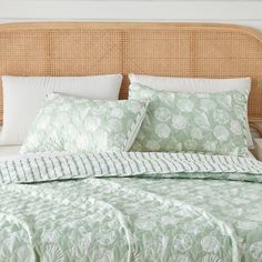 a bed with white pillows and green comforter