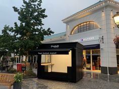 a small store with lights on the roof and trees in front of it at dusk