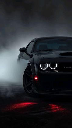 the front end of a black car with fog in the background