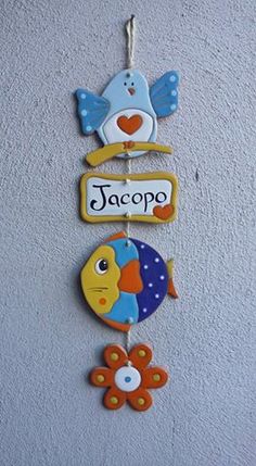 three colorful fish hanging from the side of a wall with name tags on each one