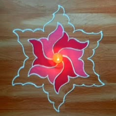 a red and white flower on a wooden floor with a lit candle in the center