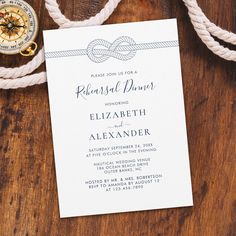 the wedding stationery is laid out on a wooden table next to a compass and rope