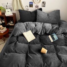 an unmade bed with two books on it and several other items sitting on the bed