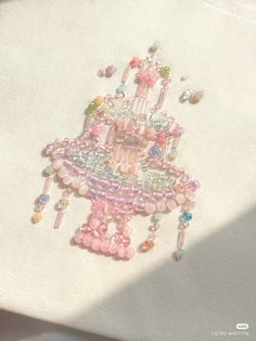 a close up view of a beaded cake on a white cloth with pink and green beads