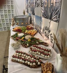 an assortment of food is displayed on a table with white linens and silverware