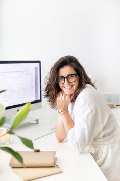 a woman sitting at a desk in front of a computer with her chin resting on her hand