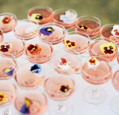 many wine glasses with flowers in them sitting on a table