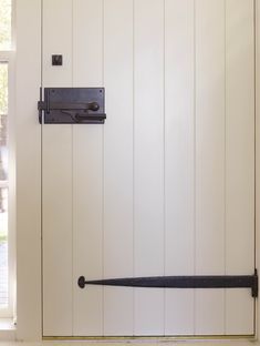 a door with a black handle on it and a window behind it that has white wood paneling