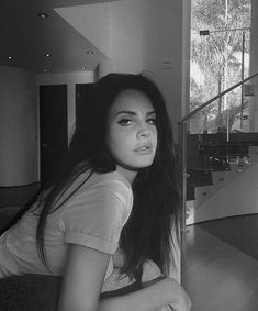 a black and white photo of a woman sitting on the floor in front of stairs