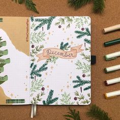 an open christmas planner next to markers and pencils on a cork board with the word december written in it