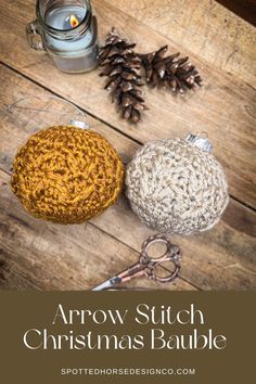 two crocheted balls sitting on top of a wooden table next to a candle