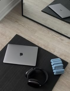 an apple laptop computer sitting on top of a mat next to headphones and yoga mats