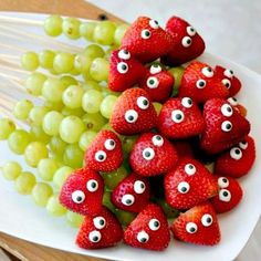 strawberries and grapes with googly eyes are on a white plate, ready to be eaten