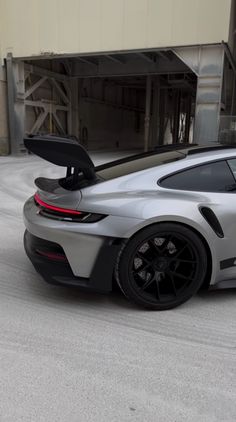 a grey sports car parked in front of a building