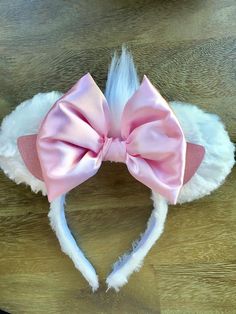 a white and pink headband with a large bow on it's side sitting on top of a wooden table