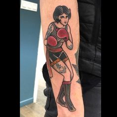 a woman with tattoos on her arm is wearing boxing gloves and holding a punching glove