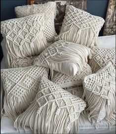 a bed topped with lots of pillows covered in crocheted white blankets and covers