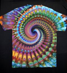 a t - shirt with a colorful spiral design on the front and back, sitting on a black surface