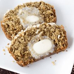 two muffins on a white plate with cream cheese in the middle and another muffin next to it