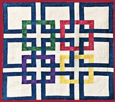 a quilted wall hanging on the side of a brick building with colorful squares and rectangles