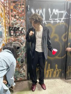 a man standing next to a wall with graffiti on it