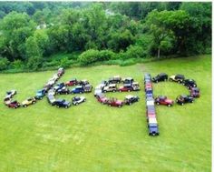 an aerial view of the word peace spelled out in cars on a grassy field surrounded by trees