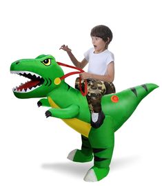 a young boy riding on the back of an inflatable t - rex costume